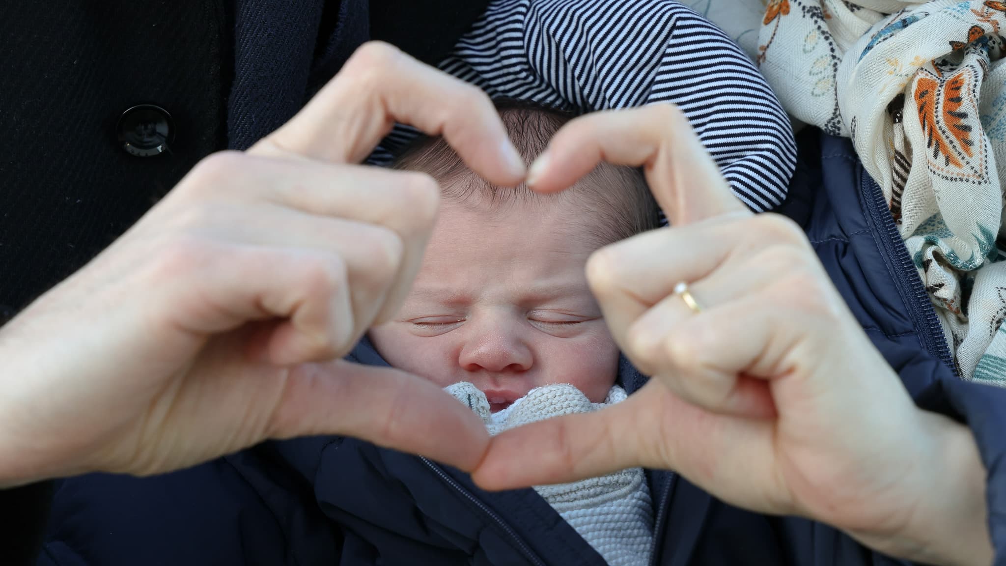 Détail de mains autour d'un nouveau-né pendant une séance famille